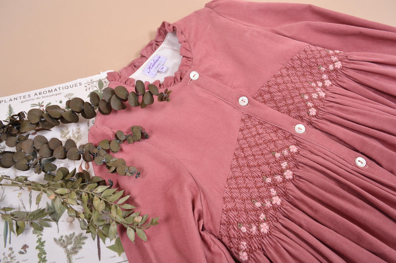 Lola, Robe à manches longues, col haut à volants, ouverture devant et smockée à la taille, en velours côtelé rose Marsala - Lola, Dress with long sleeves, high ruffled collar, front opening and smocked at the waist, in Marsala rose corduroy