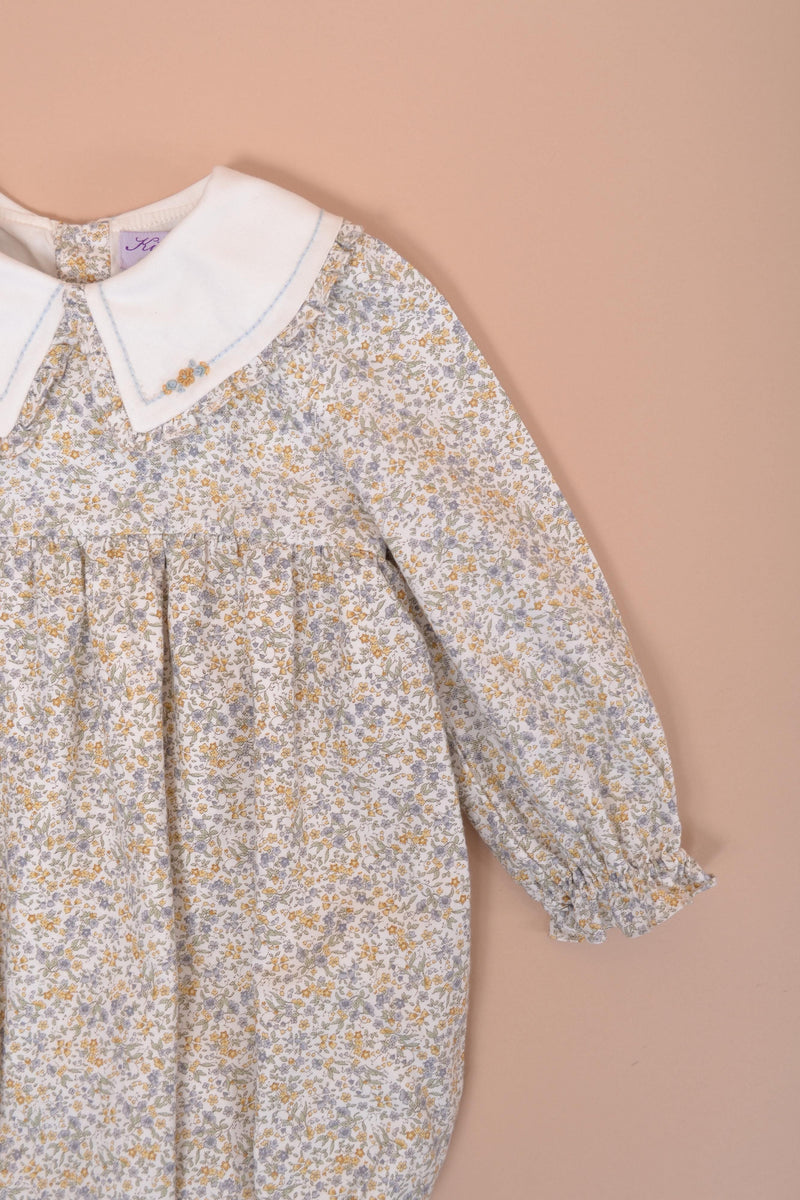 Véra, Barboteuse bébé fille manches longues, double col volanté, taille smockée, imprimé fleuri bleu ciel/moutarde - Véra, Baby girl's long-sleeved romper, double ruffled collar, smocked waist, in Sky blue/mustard floral print