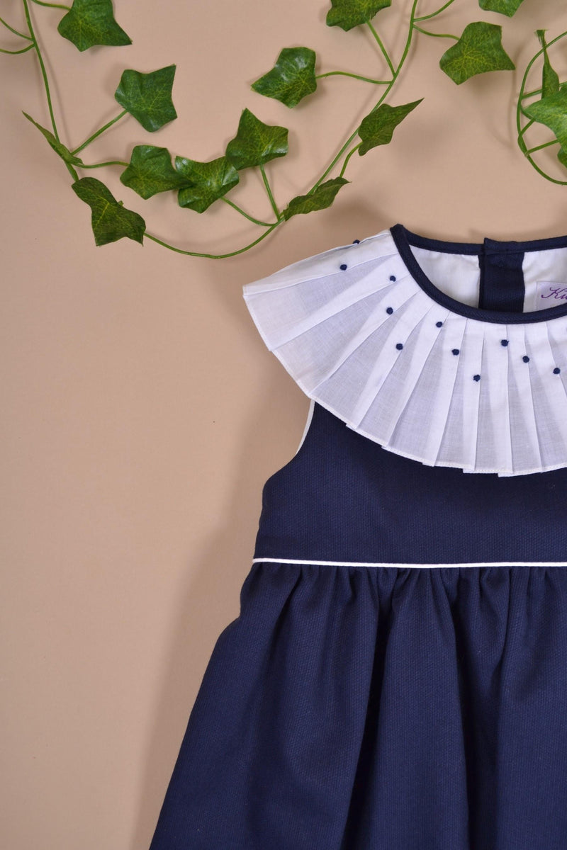 Aloé, robe sans manche avec un passepoil blanc à la taille, col plissé et brodé, en piqué de coton marine - sleeveless dress with white piping at the waist, pleated and embroidered collar, in navy cotton piqué