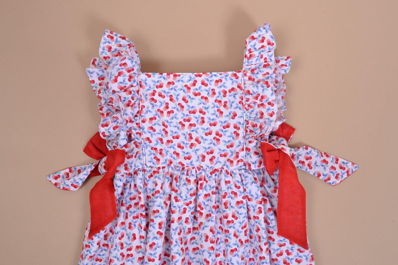 Kalanchoé, robe manches volants, encolure carrée, nœuds contrastés sur les côtés, en imprimé cerises bleues et rouges