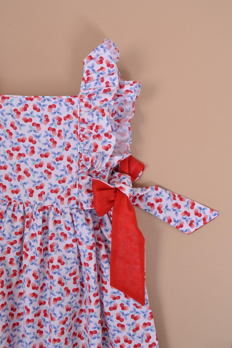 Kalanchoé, robe manches volants, encolure carrée, nœuds contrastés sur les côtés, en imprimé cerises bleues et rouges