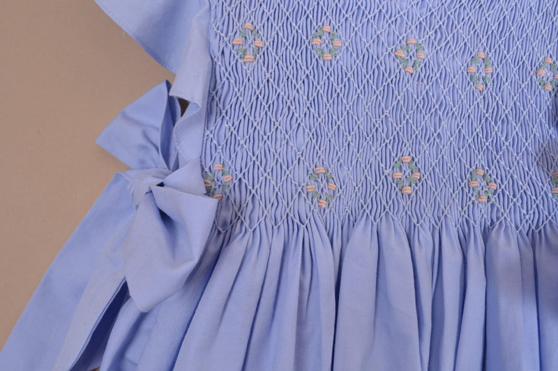 Lewisia, robe manches papillons, col rond, buste entièrement smocké, nœuds bicolores sur les côtés, en coton bio bleuet - dress with butterfly sleeves, round neck, fully smocked bust, bows on the sides, in cornflower blue organic cotton